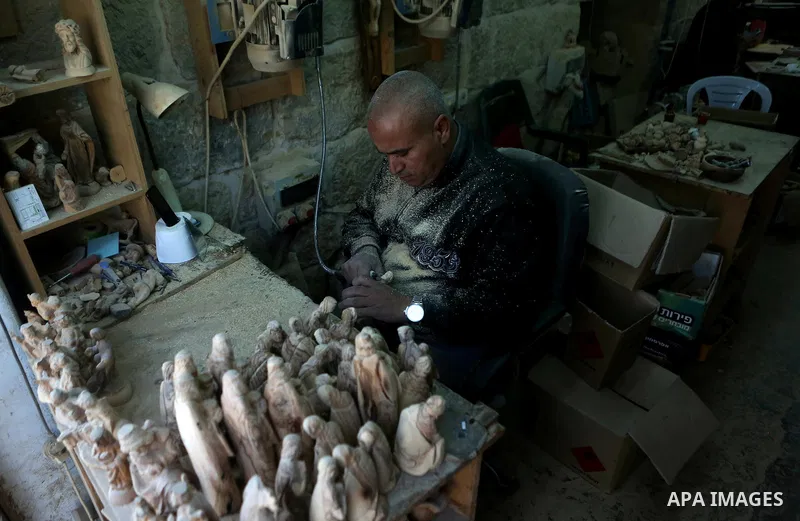 A Palestinian carpenter carves a wooden effigies of the the Holy Family at a workshop in the West Bank town of Bethlehem, on December 26, 2016. The traditional birthplace of Jesus Christ prepares to celebrate Christmas....