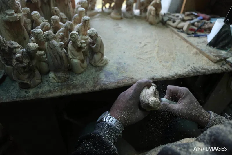 A Palestinian carpenter carves a wooden effigies of the the Holy Family at a workshop in the West Bank town of Bethlehem, on December 26, 2016. The traditional birthplace of Jesus Christ prepares to celebrate Christmas....