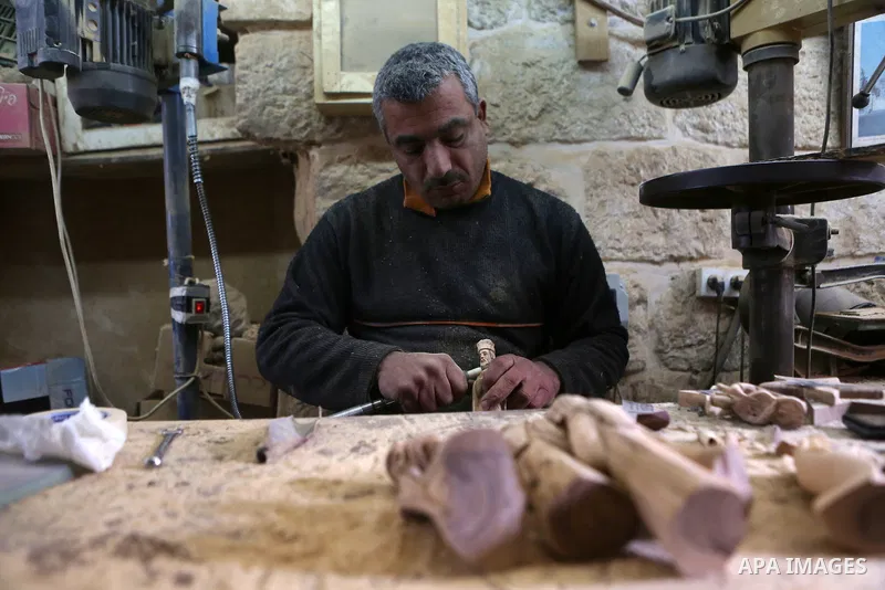 A Palestinian carpenter carves a wooden effigies of the the Holy Family at a workshop in the West Bank town of Bethlehem, on December 26, 2016. The traditional birthplace of Jesus Christ prepares to celebrate Christmas....