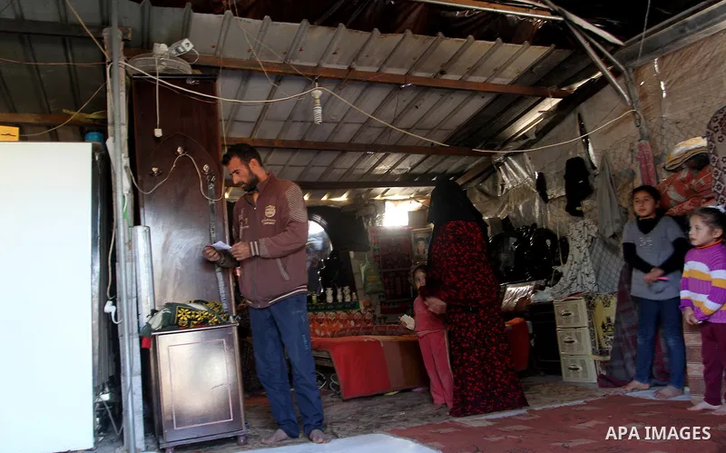Palestinian Ziad Abu Jamea, and his family sit inside his house which was destroyed during the 50-day war between Israel and Hamas militants in the summer of 2014, on in Khan Younis in the southern Gaza Strip December 26...