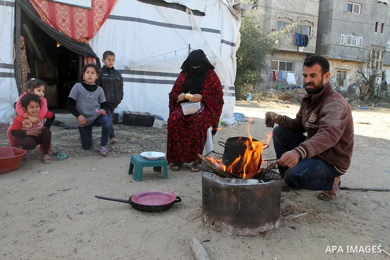 Palestinian Ziad Abu Jamea, cooks with his wife on firewood outside their house which was destroyed during the 50-day war between Israel and Hamas militants in the summer of 2014, on in Khan Younis in the southern Gaza S...
