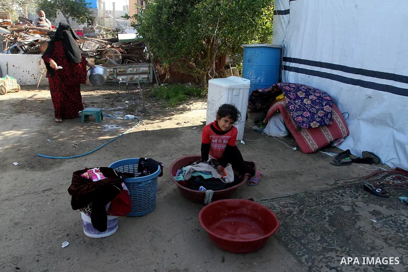 A Palestinian woman from Abu Jamea family washes pots outside her house which was destroyed during the 50-day war between Israel and Hamas militants in the summer of 2014, on in Khan Younis in the southern Gaza Strip Dec...