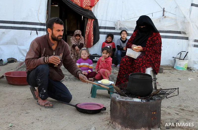 Palestinian Ziad Abu Jamea, cooks with his wife on firewood outside their house which was destroyed during the 50-day war between Israel and Hamas militants in the summer of 2014, on in Khan Younis in the southern Gaza S...