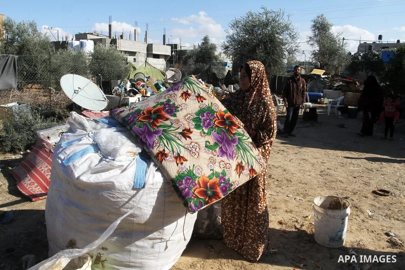 A Palestinian woman from Abu Jamea family carries their belongings outside her house which was destroyed during the 50-day war between Israel and Hamas militants in the summer of 2014, on in Khan Younis in the southern G...