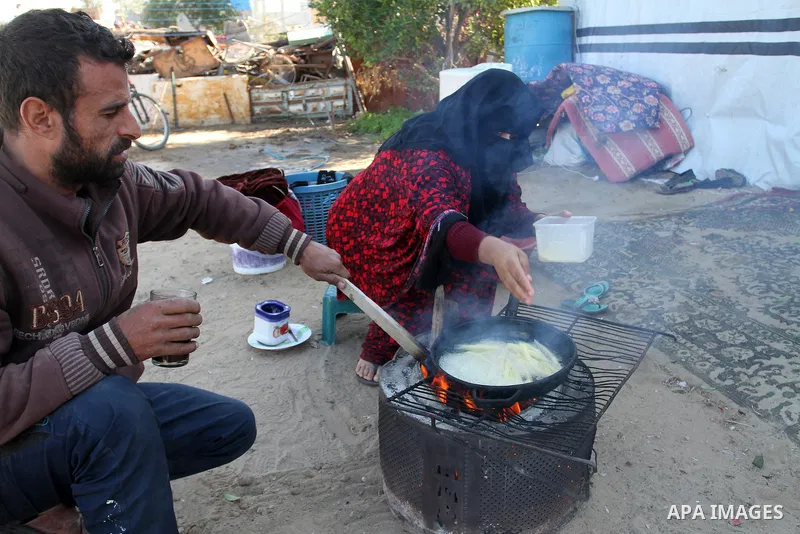 Palestinian Ziad Abu Jamea, cooks with his wife on firewood outside their house which was destroyed during the 50-day war between Israel and Hamas militants in the summer of 2014, on in Khan Younis in the southern Gaza S...