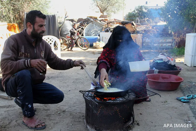 Palestinian Ziad Abu Jamea, cooks with his wife on firewood outside their house which was destroyed during the 50-day war between Israel and Hamas militants in the summer of 2014, on in Khan Younis in the southern Gaza S...