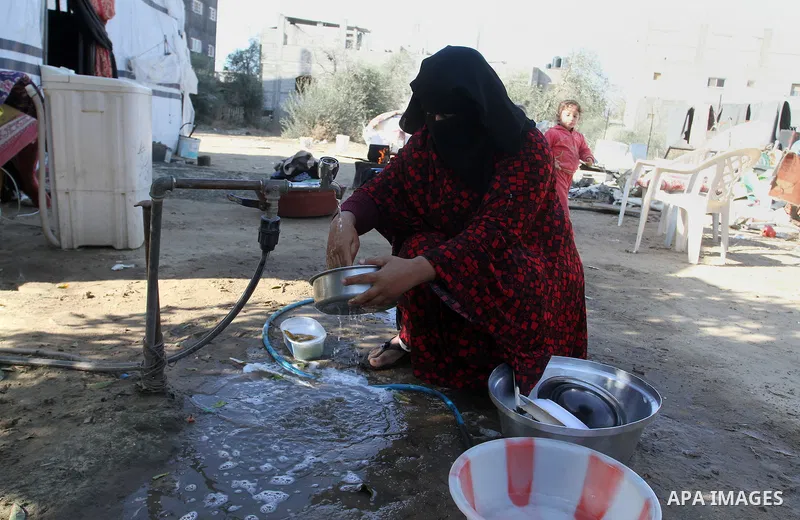 A Palestinian woman from Abu Jamea family washes pots outside her house which was destroyed during the 50-day war between Israel and Hamas militants in the summer of 2014, on in Khan Younis in the southern Gaza Strip Dec...