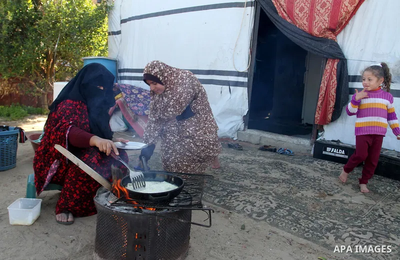 A Palestinian woman from Abu Jamea family cooks outside her house which was destroyed during the 50-day war between Israel and Hamas militants in the summer of 2014, on in Khan Younis in the southern Gaza Strip December...
