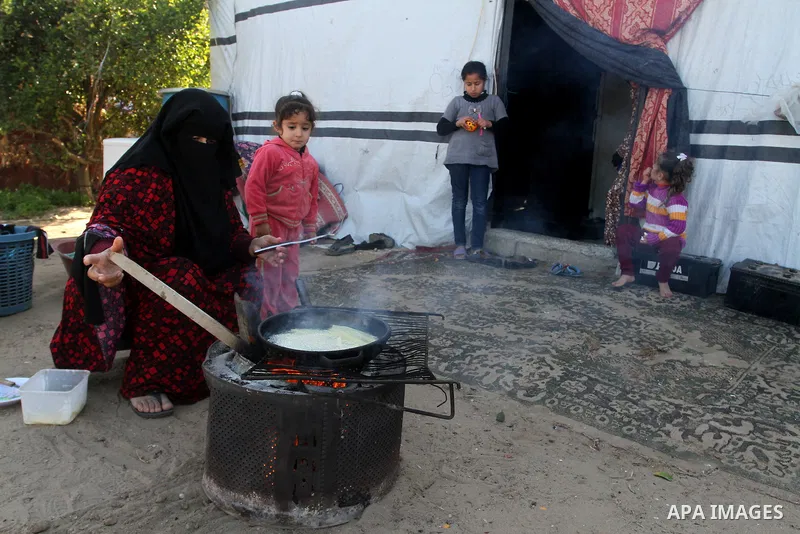 A Palestinian woman from Abu Jamea family cooks outside her house which was destroyed during the 50-day war between Israel and Hamas militants in the summer of 2014, on in Khan Younis in the southern Gaza Strip December...