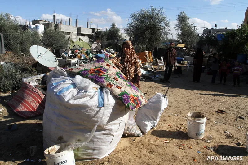 A Palestinian woman from Abu Jamea family carries their belongings outside her house which was destroyed during the 50-day war between Israel and Hamas militants in the summer of 2014, on in Khan Younis in the southern G...