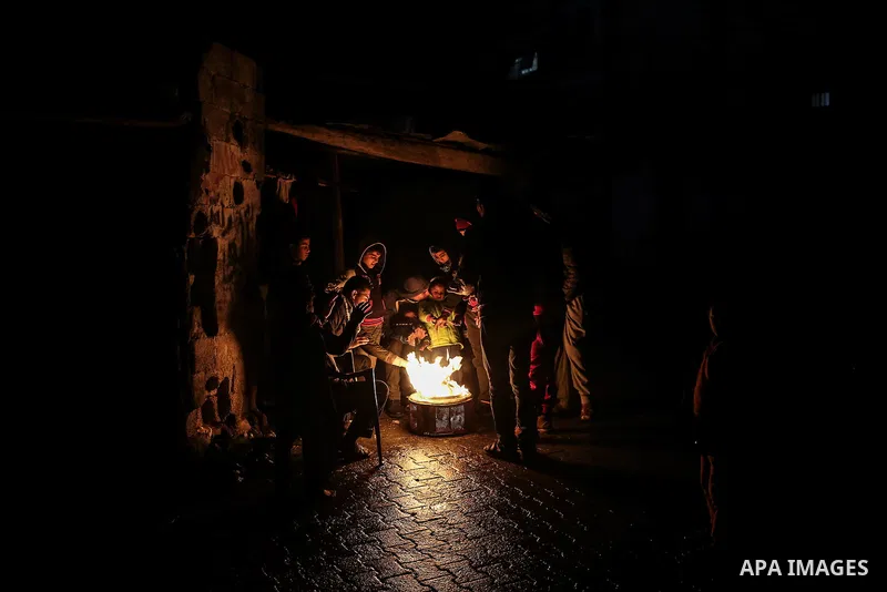 Palestinians warm themselves around a fire during the winter storm, outside their house at Al-Shate' refugee camp, in Gaza city, on December 27, 2016. Photo by Mohammed Dahman