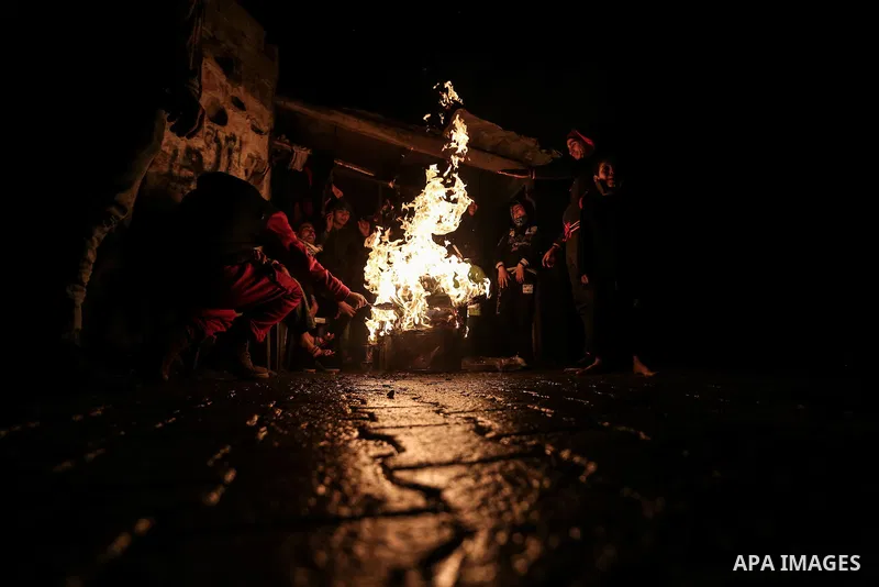 Palestinians warm themselves around a fire during the winter storm, outside their house at Al-Shate' refugee camp, in Gaza city, on December 27, 2016. Photo by Mohammed Dahman