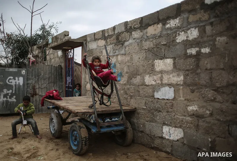 Palestinian children play during rainy, cold weather outside their family house in a slum on the outskirts of Khan Younis refugee camp, southern Gaza Strip, Wednesday, on December 28, 2016. Photo by Mohammed Dahman