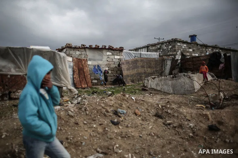 A Palestinian man walks outside his house during rainy, cold weather in a slum on the outskirts of Khan Younis refugee camp, southern Gaza Strip, on December 28, 2016. Photo by Mohammed Dahman