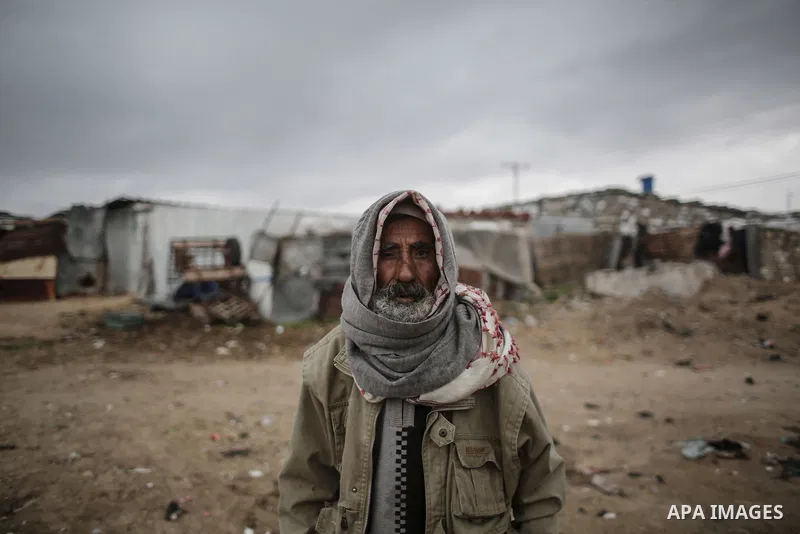 A Palestinian man poses for a photo during rainy, cold weather outside his house in a slum on the outskirts of Khan Younis refugee camp, southern Gaza Strip, on December 28, 2016. Photo by Mohammed Dahman
