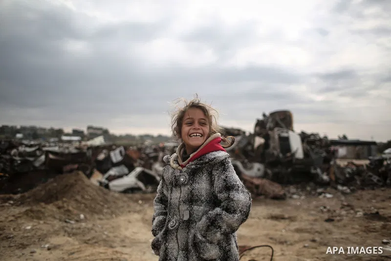 A Palestinian girl poses for a photo during rainy, cold weather outside her family house in a slum on the outskirts of Khan Younis refugee camp, southern Gaza Strip, on December 28, 2016. Photo by Mohammed Dahman