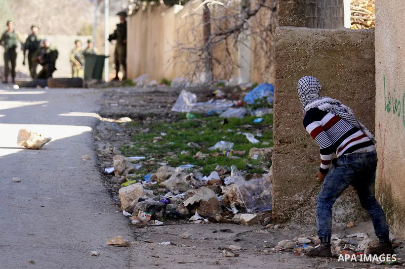 A Palestinian protester takes cover during clashes with Israeli security forces following a demonstration against the expropriation of Palestinian land by Israel in the village of Kfar Qaddum, near Nablus, in the occupie...
