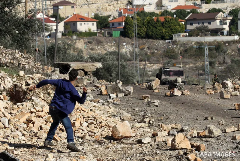 A Palestinian protester hurls stones during clashes with Israeli security forces following a demonstration against the expropriation of Palestinian land by Israel in the village of Kfar Qaddum, near Nablus, in the occupi...