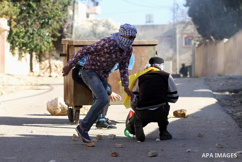 Palestinian protesters take cover during clashes with Israeli security forces following a demonstration against the expropriation of Palestinian land by Israel in the village of Kfar Qaddum, near Nablus, in the occupied...