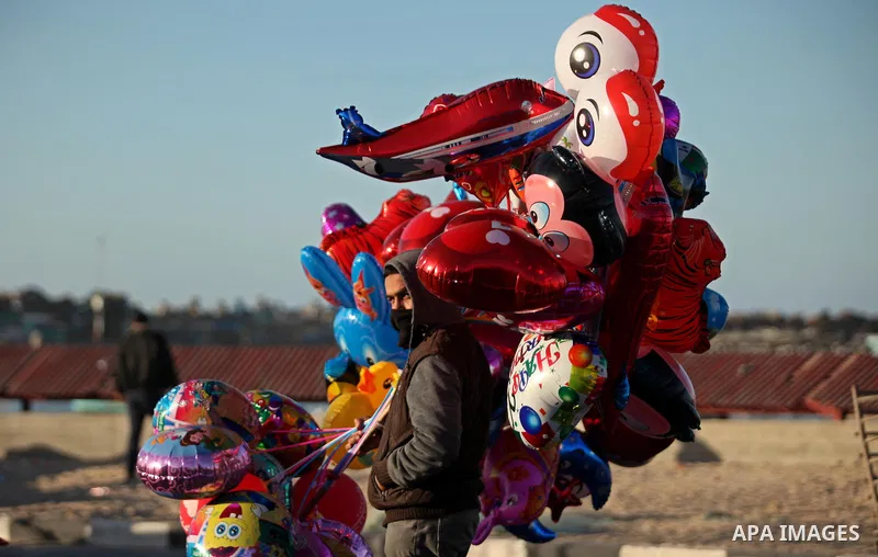 A Palestinian vendor sells balloons, during take part in celebrations of the New Year's Eve festivities at the Gaza seaport, on December 31, 2016. Photo by Ashraf Amra