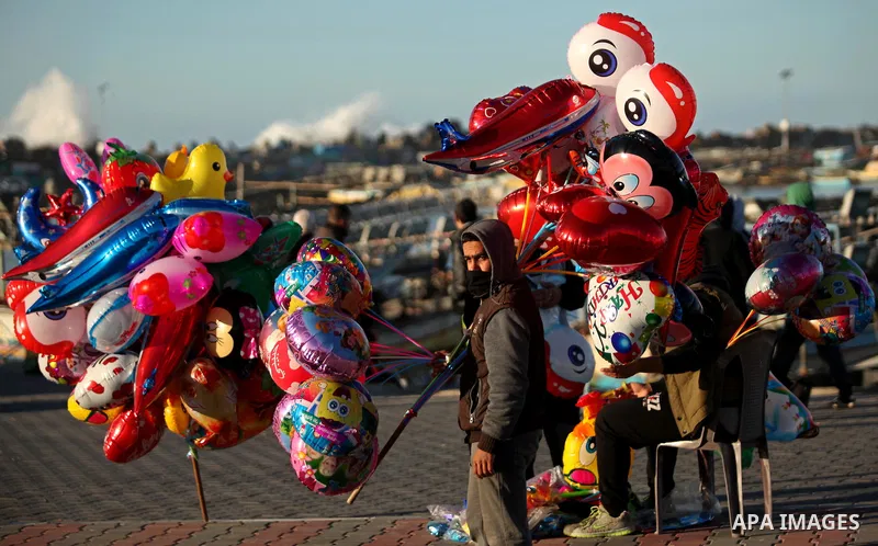 A Palestinian vendor sells balloons, during take part in celebrations of the New Year's Eve festivities at the Gaza seaport, on December 31, 2016. Photo by Ashraf Amra