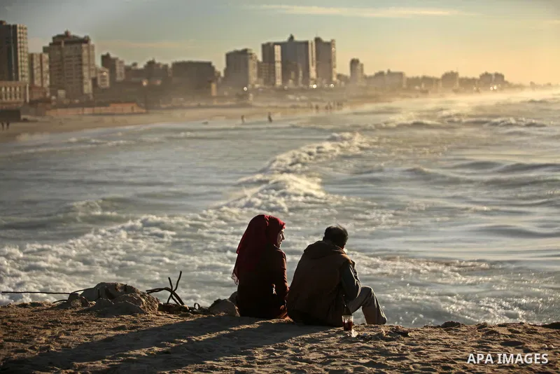Palestinians sit on the beach of Gaza City as they enjoyed the last sunset of 2016, on December 31, 2016. Photo by Ashraf Amra