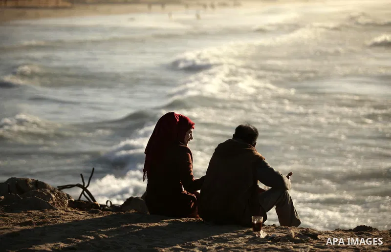 Palestinians sit on the beach of Gaza City as they enjoyed the last sunset of 2016, on December 31, 2016. Photo by Ashraf Amra