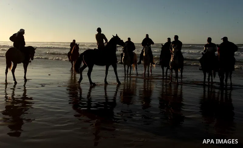 Palestinian men ride their horse as they enjoy the last sunset of 2016 at the beach of Gaza city, on the December 31, 2016. Photo by Ashraf Amra
