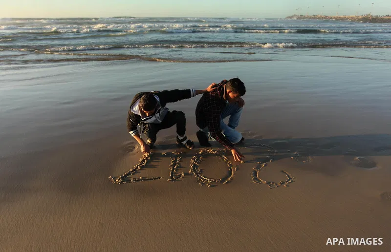 Palestinian girls write on a sand read "2017" during the last sunset of 2016 on the beach of Gaza City, on December 31, 2016. Photo by Ashraf Amra