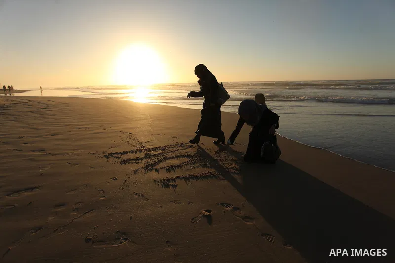Palestinian girls write on a sand read "2017" during the last sunset of 2016 on the beach of Gaza City, on December 31, 2016. Photo by Ashraf Amra