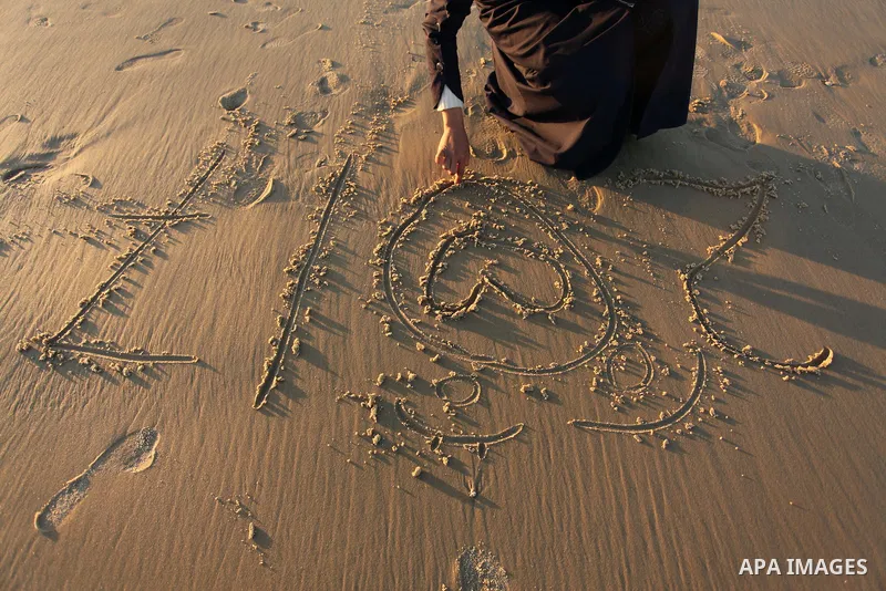 A Palestinian girl writes on a sand read "2017" during the last sunset of 2016 on the beach of Gaza City, on December 31, 2016. Photo by Ashraf Amra