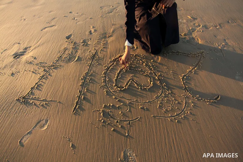 A Palestinian girl writes on a sand read "2017" during the last sunset of 2016 on the beach of Gaza City, on December 31, 2016. Photo by Ashraf Amra