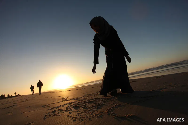 A Palestinian girl writes on a sand read "2017" during the last sunset of 2016 on the beach of Gaza City, on December 31, 2016. Photo by Ashraf Amra