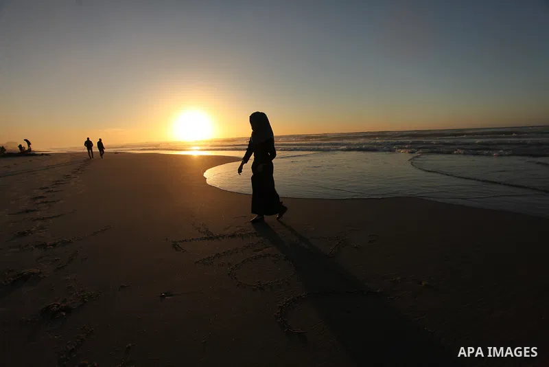 A Palestinian girl writes on a sand read "2017" during the last sunset of 2016 on the beach of Gaza City, on December 31, 2016. Photo by Ashraf Amra