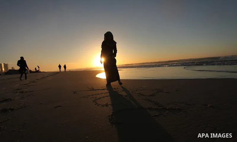 A Palestinian girl writes on a sand read "2017" during the last sunset of 2016 on the beach of Gaza City, on December 31, 2016. Photo by Ashraf Amra