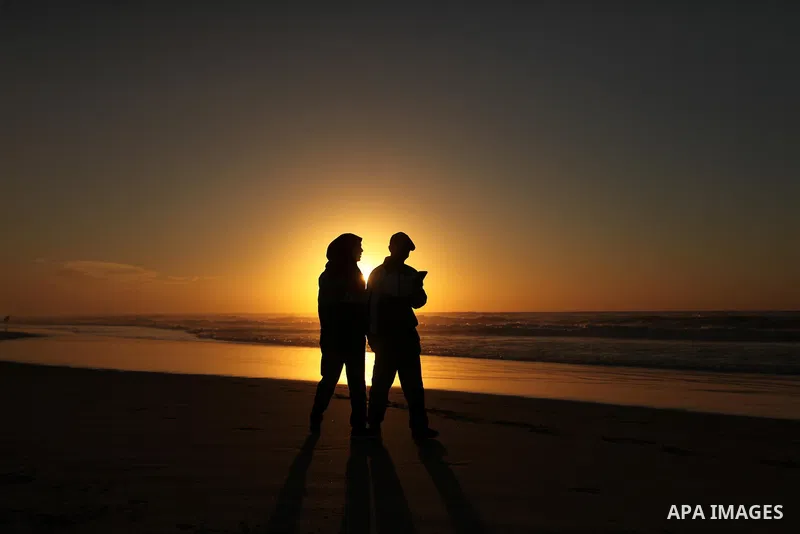 Palestinians walk on the beach of Gaza City, during the last sunset of 2016, on December 31, 2016. Photo by Ashraf Amra