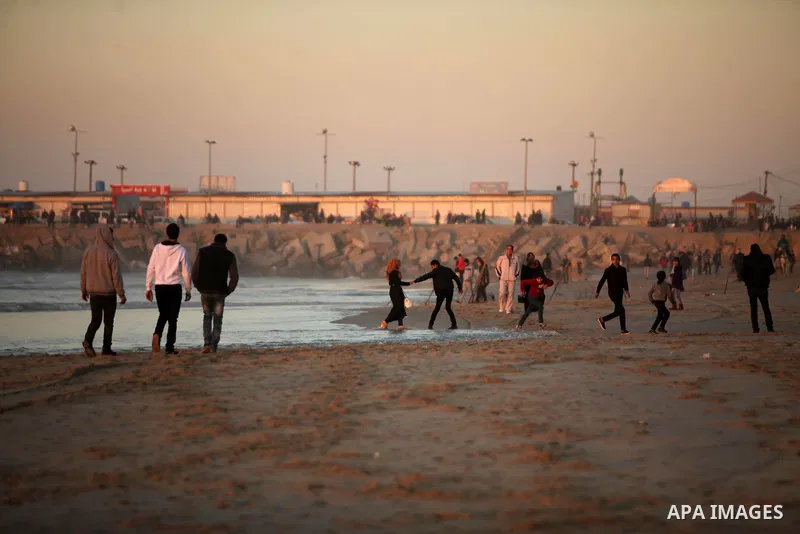 Palestinians walk on the beach of Gaza City, during the last sunset of 2016, on December 31, 2016. Photo by Ashraf Amra
