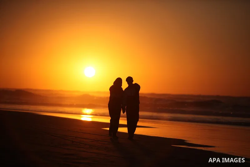 Palestinians walk on the beach of Gaza City, during the last sunset of 2016, on December 31, 2016. Photo by Ashraf Amra