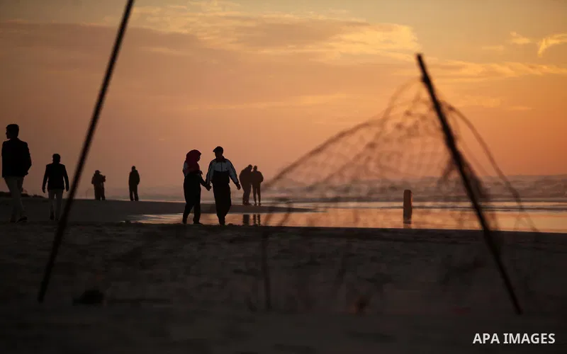 Palestinians walk on the beach of Gaza City, during the last sunset of 2016, on December 31, 2016. Photo by Ashraf Amra