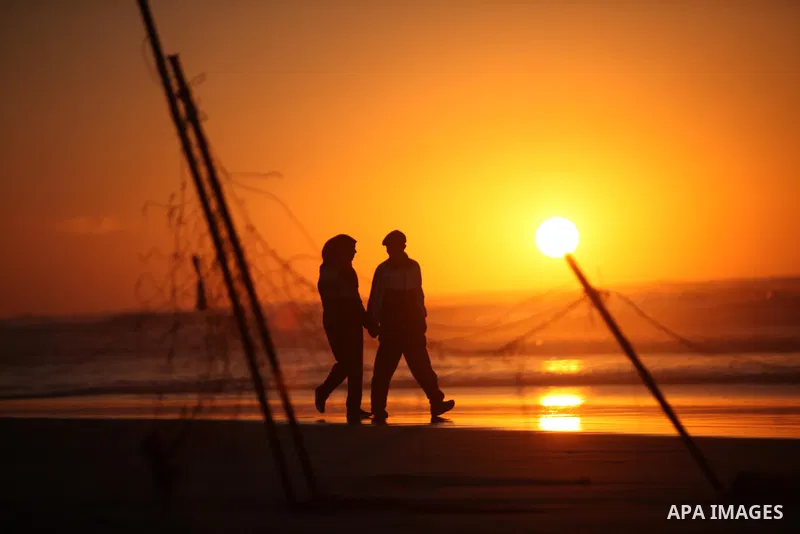 Palestinians walk on the beach of Gaza City, during the last sunset of 2016, on December 31, 2016. Photo by Ashraf Amra