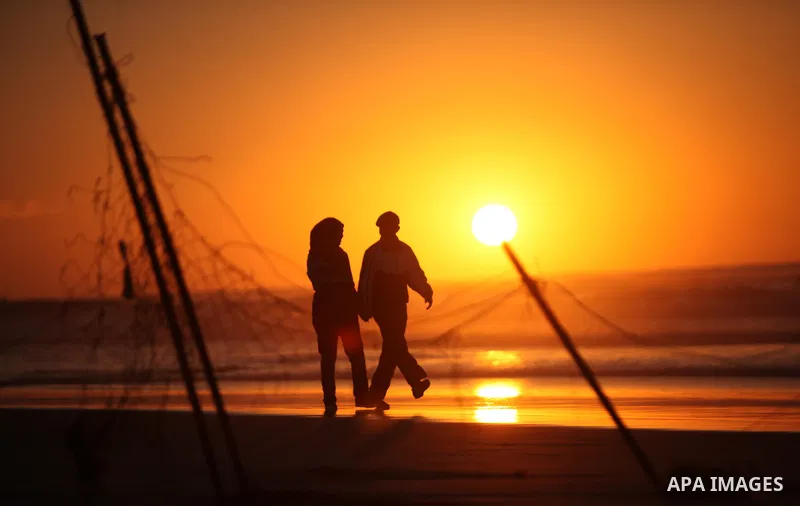 Palestinians walk on the beach of Gaza City, during the last sunset of 2016, on December 31, 2016. Photo by Ashraf Amra