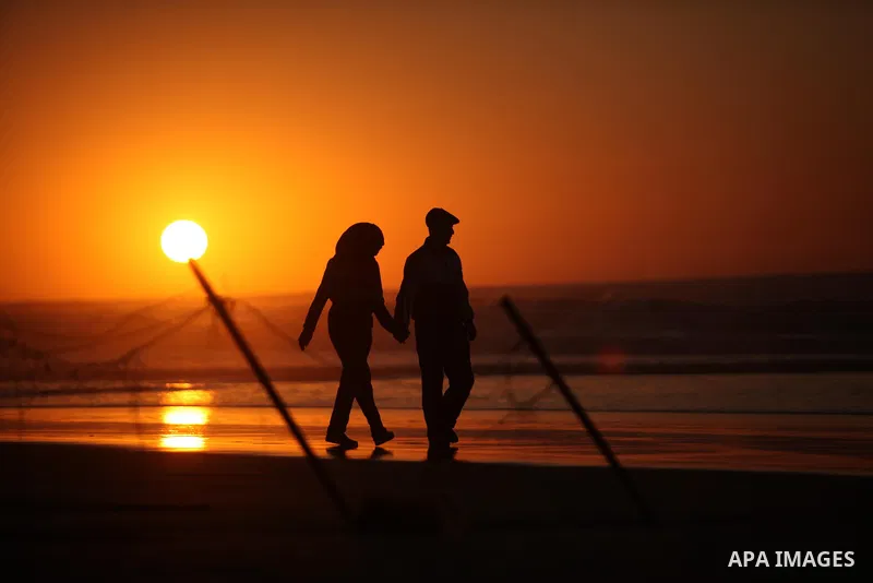 Palestinians walk on the beach of Gaza City, during the last sunset of 2016, on December 31, 2016. Photo by Ashraf Amra