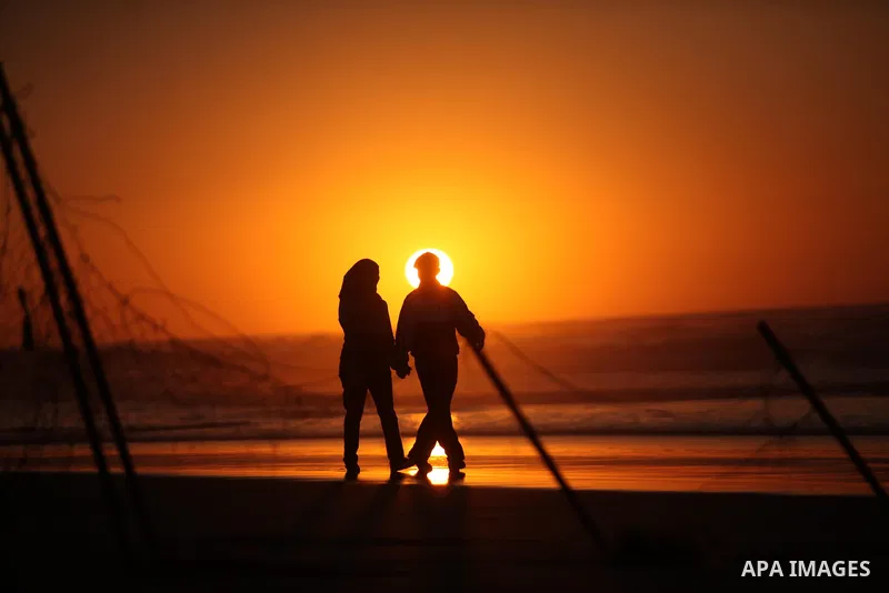 Palestinians walk on the beach of Gaza City, during the last sunset of 2016, on December 31, 2016. Photo by Ashraf Amra
