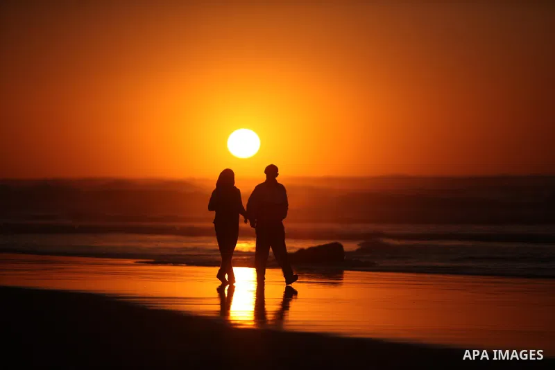 Palestinians walk on the beach of Gaza City, during the last sunset of 2016, on December 31, 2016. Photo by Ashraf Amra