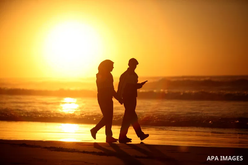 Palestinians walk on the beach of Gaza City, during the last sunset of 2016, on December 31, 2016. Photo by Ashraf Amra