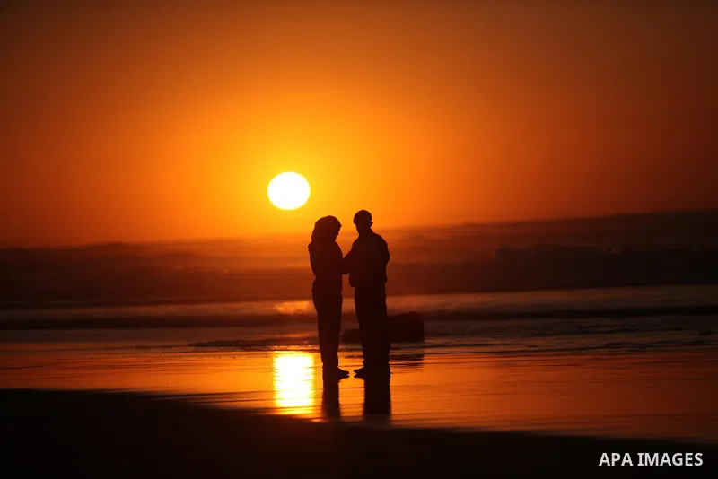Palestinians walk on the beach of Gaza City, during the last sunset of 2016, on December 31, 2016. Photo by Ashraf Amra