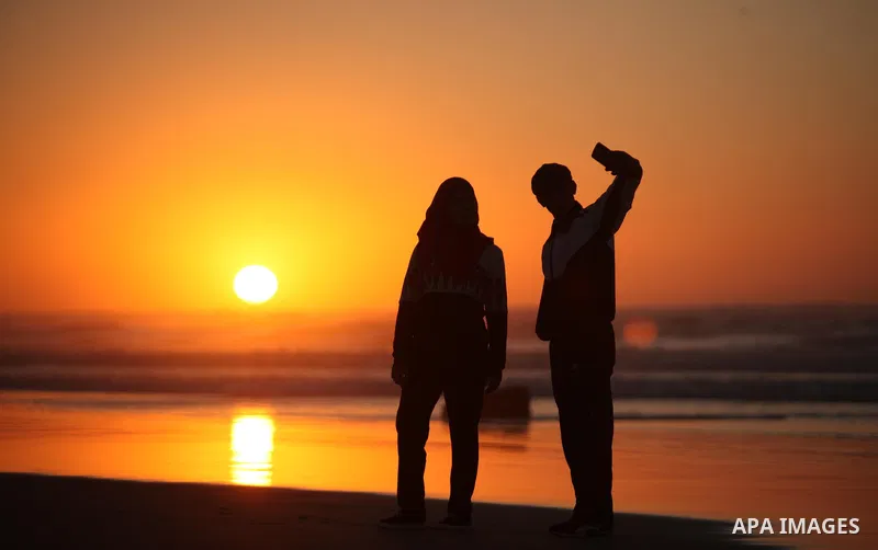 Palestinians take a selfie on the beach of Gaza City, during the last sunset of 2016, on December 31, 2016. Photo by Ashraf Amra