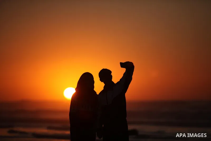 Palestinians take a selfie on the beach of Gaza City, during the last sunset of 2016, on December 31, 2016. Photo by Ashraf Amra