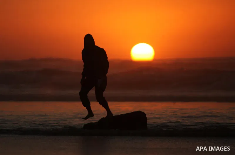 A Palestinian man walks on the beach of Gaza City, during the last sunset of 2016, on December 31, 2016. Photo by Ashraf Amra