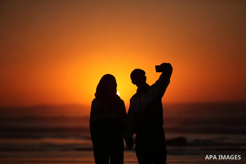 Palestinians take a selfie on the beach of Gaza City, during the last sunset of 2016, on December 31, 2016. Photo by Ashraf Amra